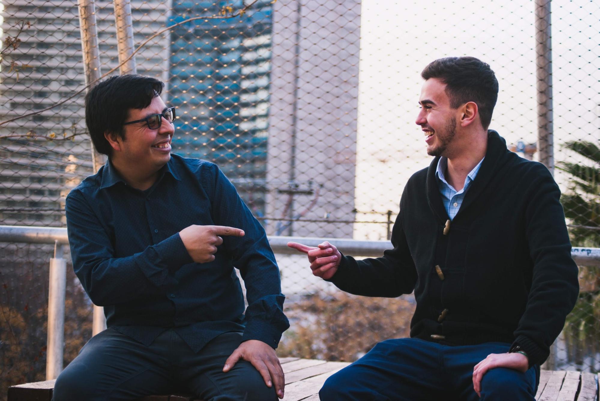 Two men laughing together and pointing at each other