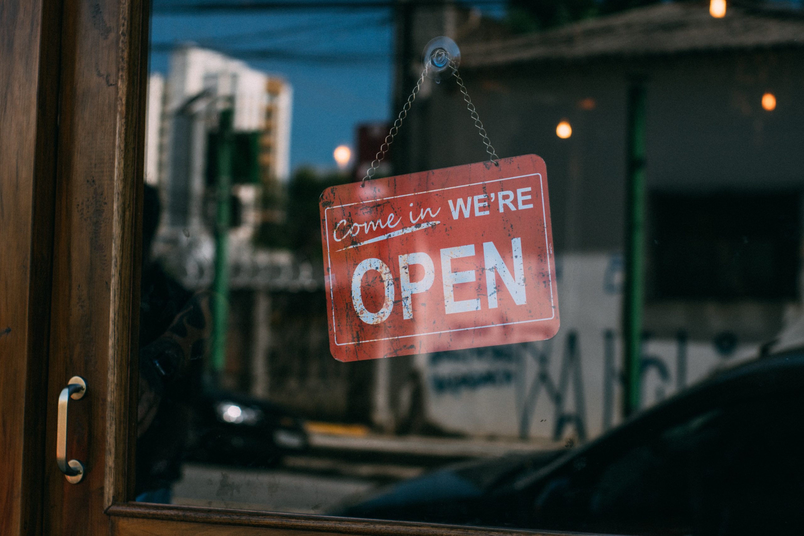 Come in we're open sign in the window of a door