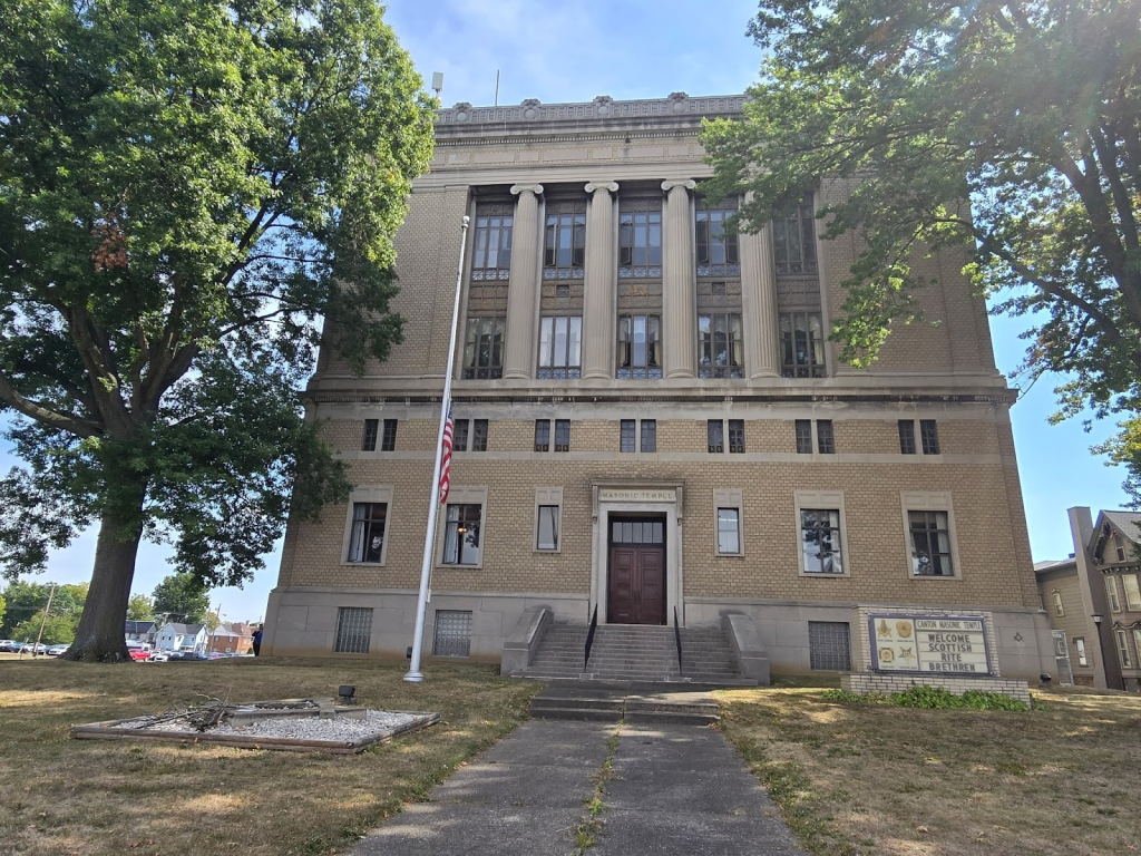 Photo of the Canton Masonic Temple, the building is tan and is surrounded by two big trees.